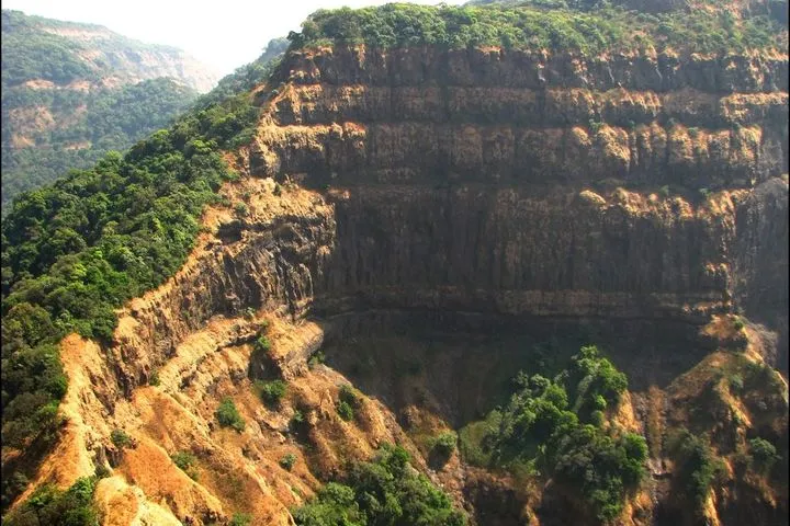 Steep layered rock cliffs of Vasota Fort surrounded by the dense jungle of the Koyna backwaters