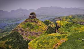 The rocky pyramidal summit of Ratangad Fort with tiered stone layers and green monsoon slopes