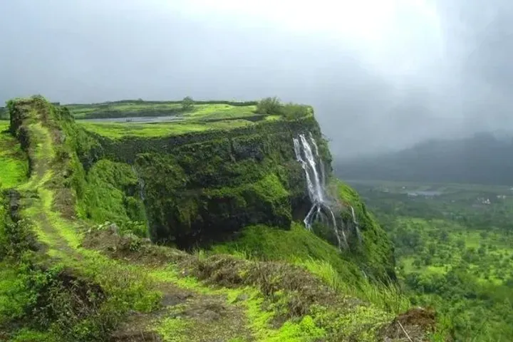 The overhanging Konkan Kada cliff of Harishchandragad curving above a deep green valley
